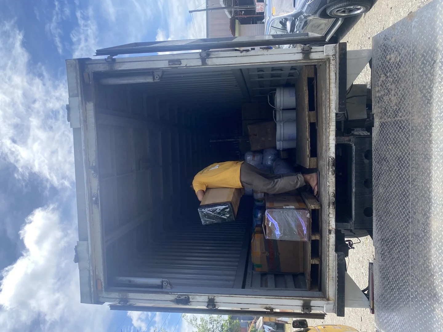 Worker carefully loading boxed cargo into delivery truck for fast transit