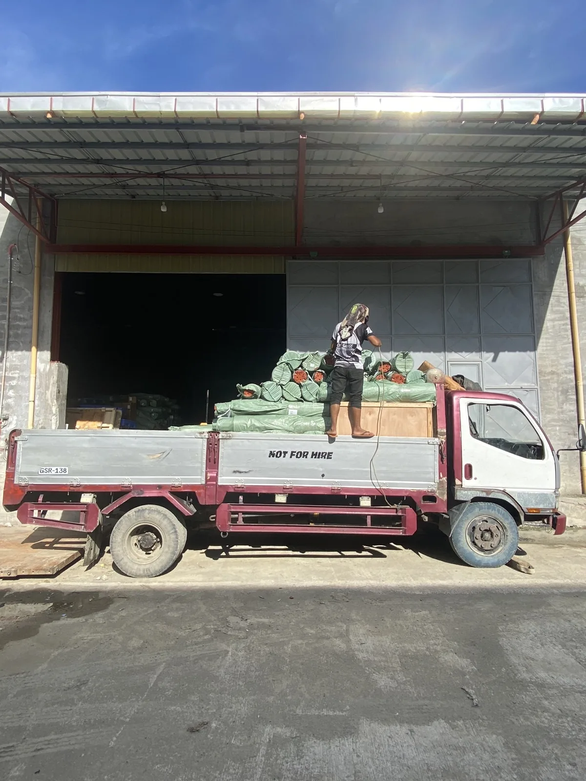 Flatbed truck loaded with cargo at Jeoffel warehouse loading dock, workers securing goods for delivery