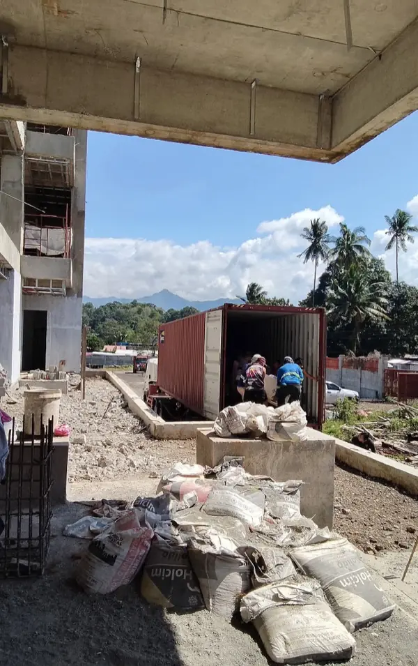 Worker unloading cargo from shipping container into warehouse
