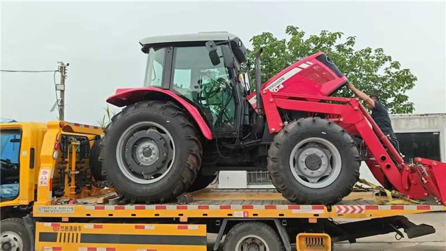 Red farm tractor loaded on a Chinese flatbed transport truck, ready for sea freight export to the Philippines