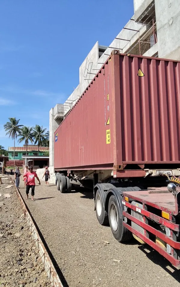 Red shipping container truck carrying cargo at port